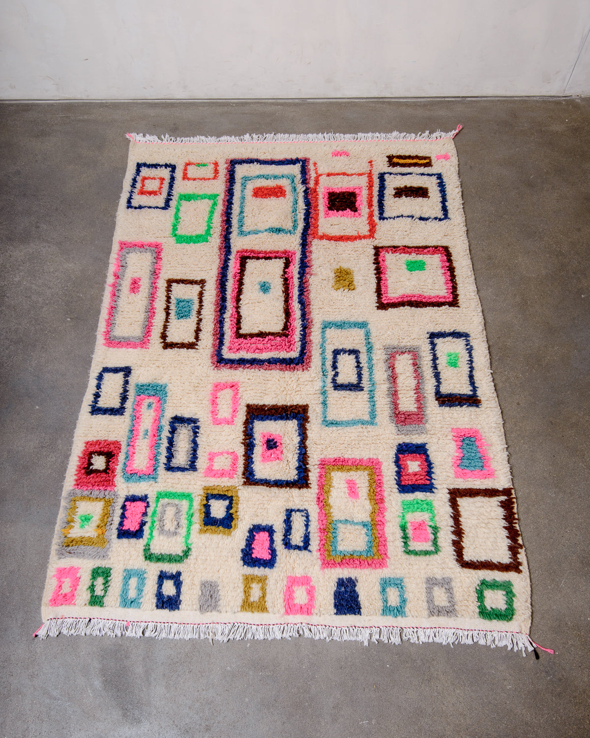 Berberlin Azilal rug with colourful design laying flat on concrete floor.